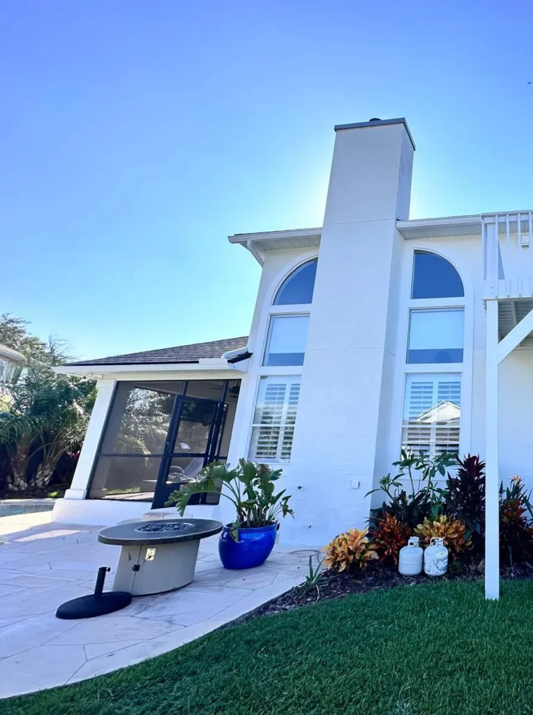 Two-story white home with a freshly painted chimney, arched windows and a screened lanai, Florida