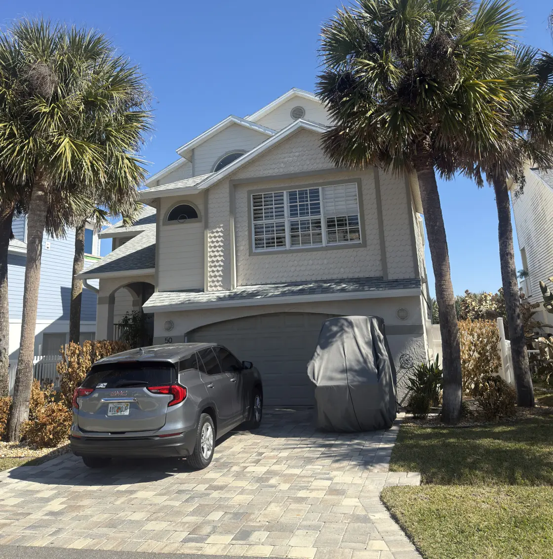 Two-story home exterior freshly painted in cream, framed by palm trees, Florida