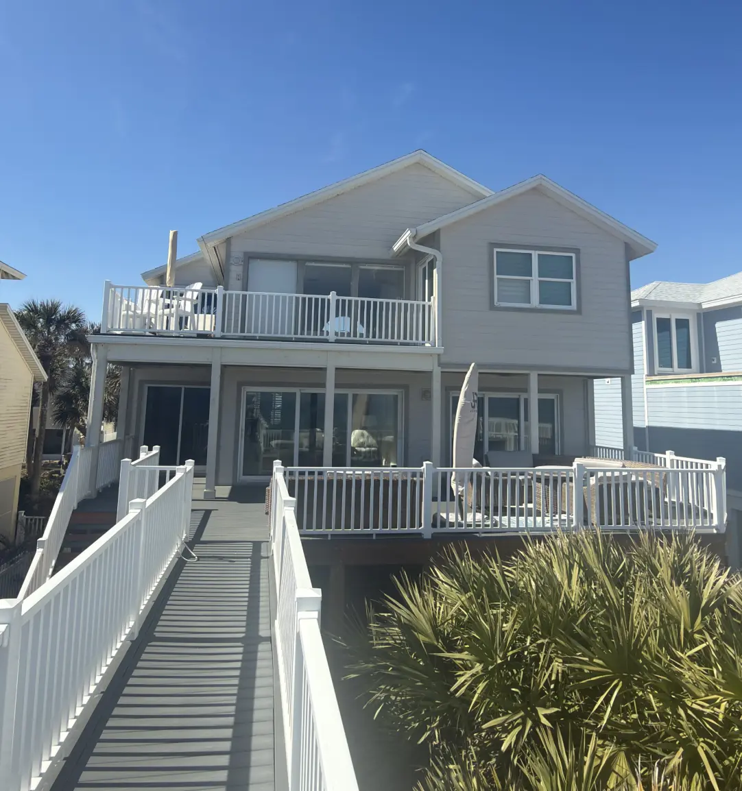 Three-story coastal home freshly painted in gray with white railings and balconies, Florida
