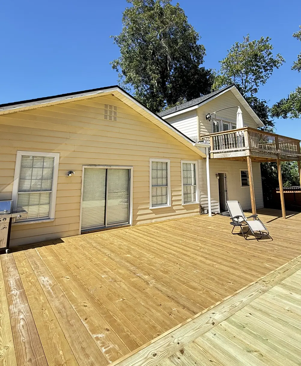 Two-story home exterior freshly painted in cream with a wood deck, Florida