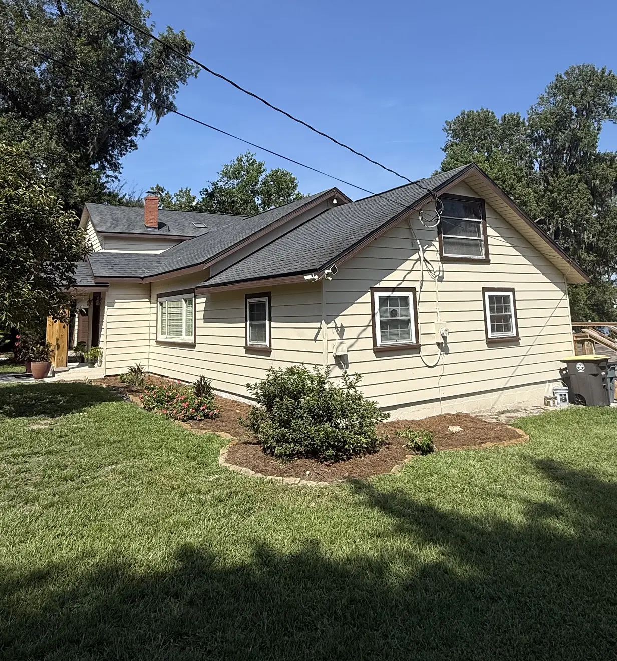 Wood-siding bungalow with a freshly painted cream exterior and dark roof, Florida