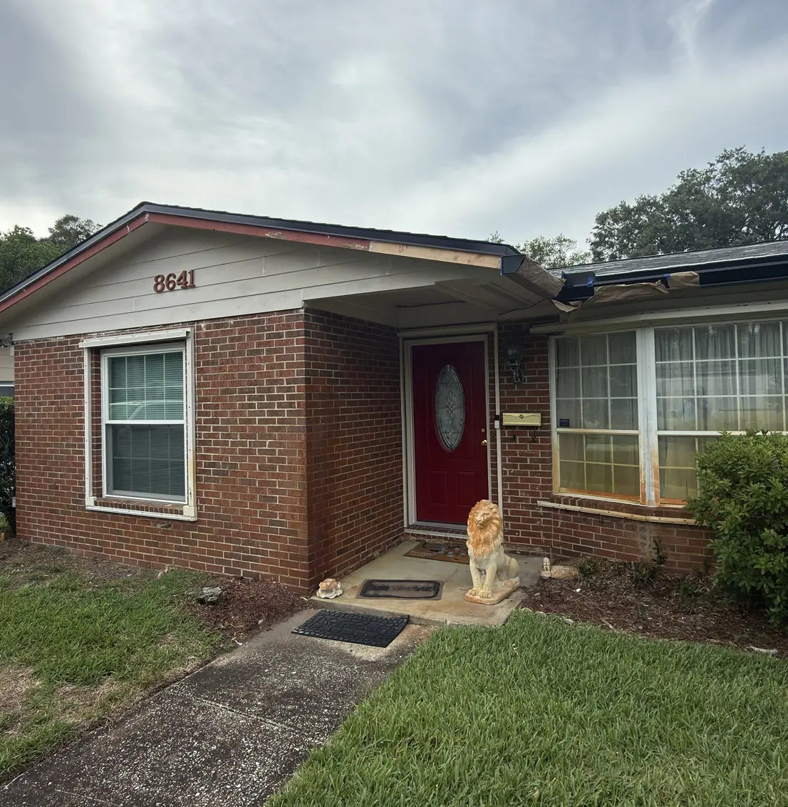 Single-story brick home with freshly painted trim and a red front door, Florida