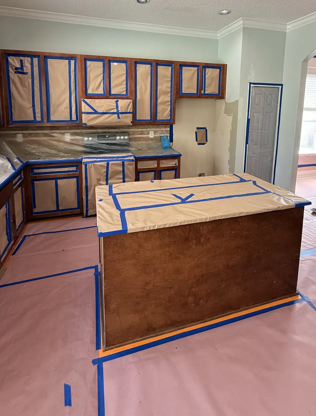 Kitchen cabinets masked with painter's tape during a cabinet repaint, Florida